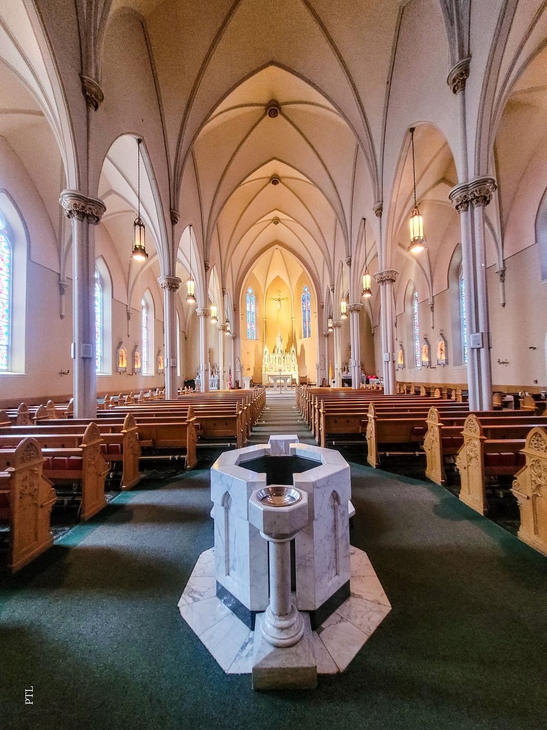 The nave of St. Mary's — vaulted ceiling, stained glass, marble baptismal font